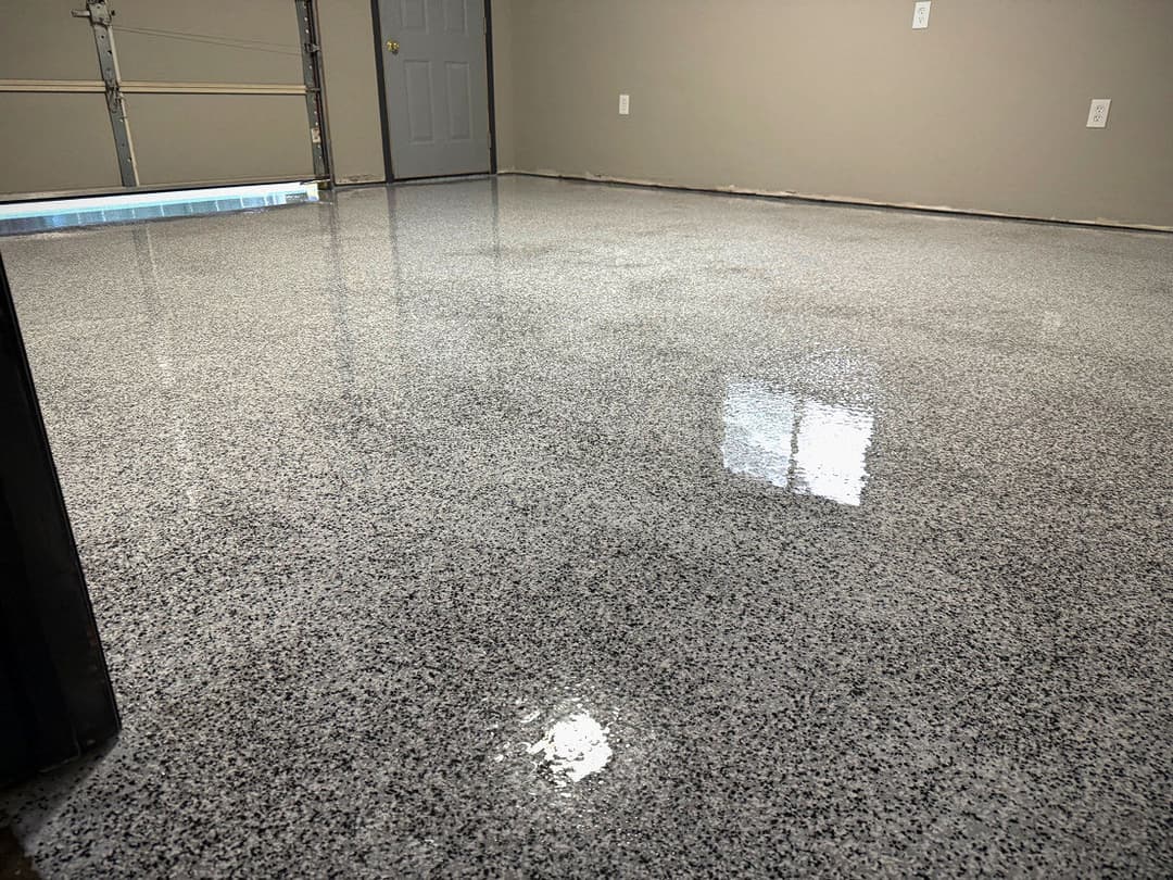 Shiny epoxy garage floor with gray specks in a clean, empty space.