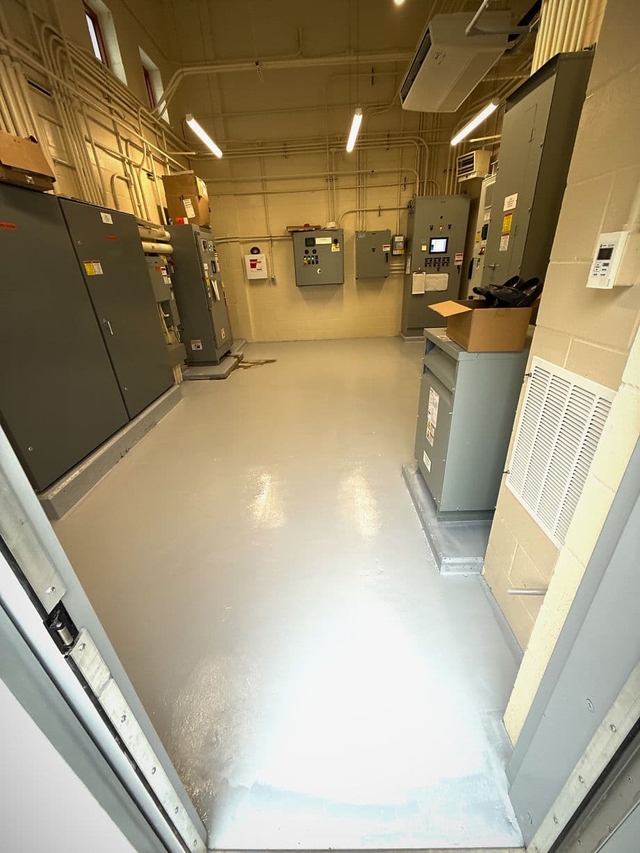 Industrial control room with gray cabinets, equipment, and freshly painted floor.