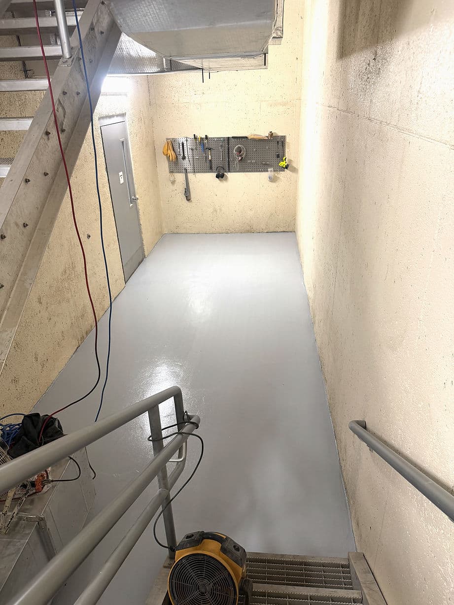 Clean, freshly painted stairwell with tools on a wall and industrial lighting.